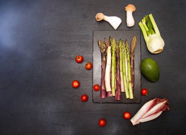 Sağlıklı yemek hazırlanması için malzemeler. Kiraz domates, kuşkonmaz, cherry domates, hindiba, rezene, avokado, siyah arka plan üzerinde istiridye mantar. Düz yatıyordu. Yükü. Kopya alanı.