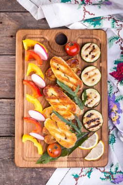 Set collection of cheese and snacks. Grilled halloumi, pepper, zuccini, tomato cherry and radish over on old wooden rustic background. Overhead.  clipart