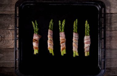 Sopa yeşil kuşkonmaz pastırma prosciutto jambon siyah fırın tepsisi arka plan ile sarılmış. Overhad. Üstten görünüm.