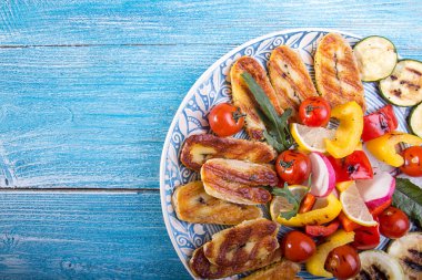 Peynir ve aperatifler koleksiyonu ayarla. Izgara Hellim, biber, zuccini, domates kiraz ve mavi ahşap zemin üzerinde turp. Yükü. Kopya alanı.