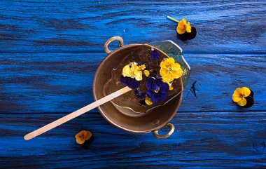 Güzel lolipop karamel vintage üzerinde yenilebilir mor çiçekli üzerinde koyu mavi arka plan üzerinde kase cooper. Üstten Görünüm. Yükü. Kopya alanı.