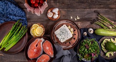 Akşam yemeği hazırlamak için farklı tabakları içeren genel kompozisyon: kuşkonmaz, somon, pastırma, mantar, domates, kabak, avokado vs. Üst Manzara. Boşluğu kopyala