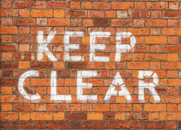 Keep Clear sign painted on brick wall