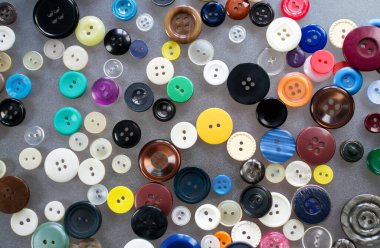 Çok renkli eski plastik düğmeler masanın üzerinde gelişigüzel duruyor.