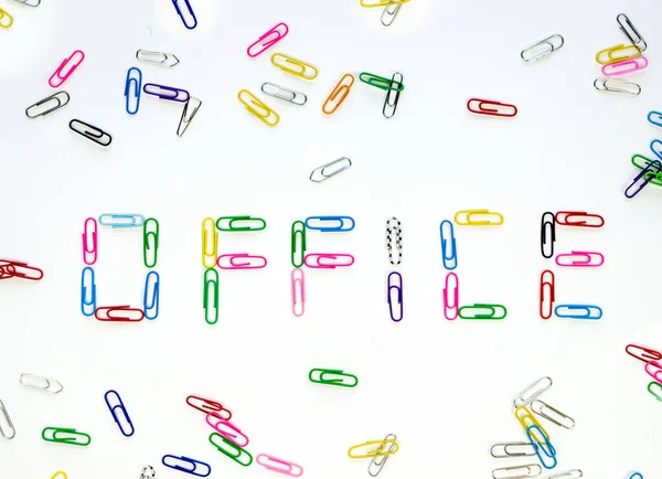 Made up of multi-colored paper clips the word office on a white background surrounded by other colored paper clips