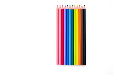 Gökkuşağının her renginden renkli kalemler beyaz bir arkaplanda dikey olarak yatar.