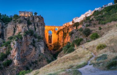 Ronda and its historic bridge illuminated in the evening. Province of Malaga, Andalusia, Spain. clipart