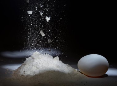 Karanlık bir arka plan üzerine düşen un ve tavuk yumurta