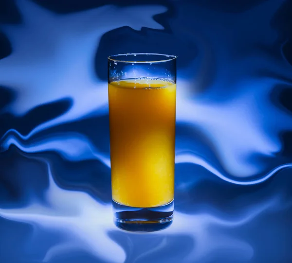 青い背景の新鮮なオレンジ ジュースのガラス — ストック写真
