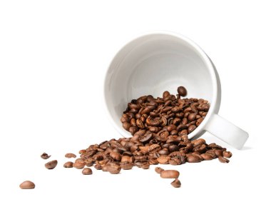 Kahve çekirdekleri düşmüş bir bardaktan dağınık. Beyaz arka plan izole. Yakın çekim.