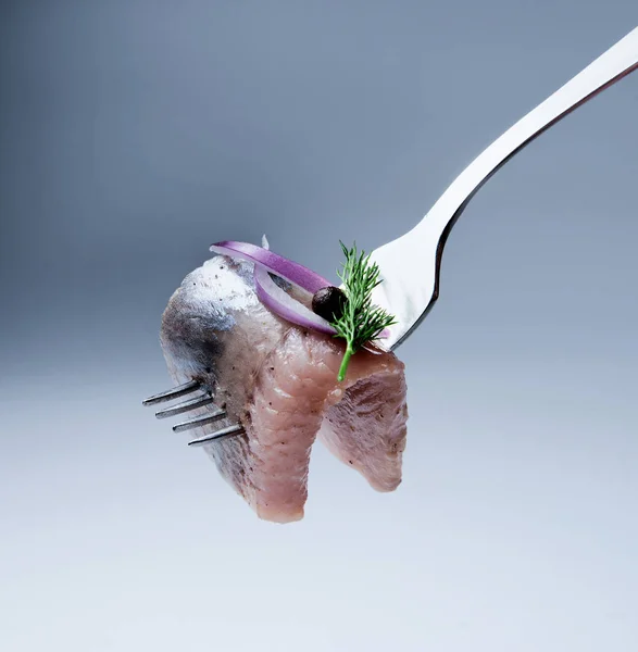 Bir parça çatal taze ringa dere otu, kırmızı soğan ve tatlı bezelye sapı ile dekore edilmiştir. Mavi tonu arka plan.