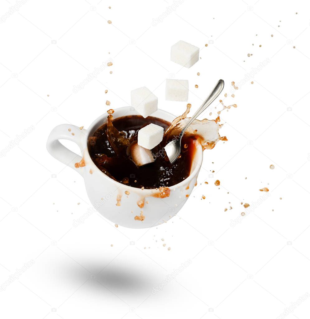 A falling cup of coffee, sugar cubes and a spoon. Bursts and drops. Motion. Shadow. White isolated background. View from above.
