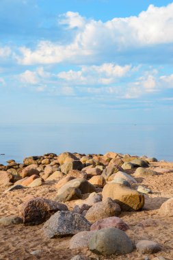 Körfezin kıyısında granit taşlardan oluşan bir zincir. Yaz sabahı erken den. Parlak mavi gökyüzü ve cirrus bulutlar.