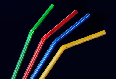 Siyah bir arka plan üzerinde bir kokteyl için birkaç çok renkli tüpler. Yakın çekim ve canlı doymuş renkler.