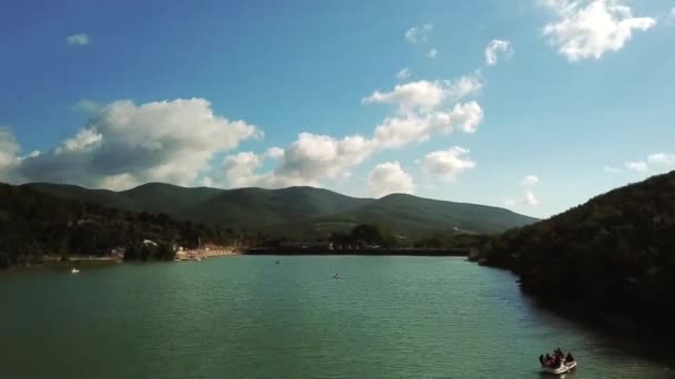 Quadrocopter se eleva por encima de la vista del lago de los catamaranes de las montañas en el agua — Vídeo de stock