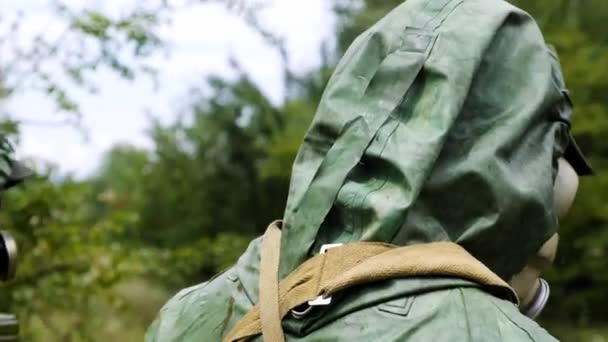 Tre militära män i en skyddande dräkt i en gasmask gå igenom Tjernobyl i skogen — Stockvideo