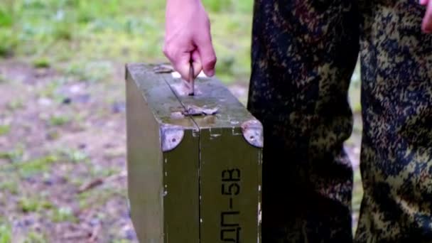 Soldat der Militärkadette in Baskenmützen legt eine grüne Schachtel auf den Boden im Feld von Tschernobyl — Stockvideo