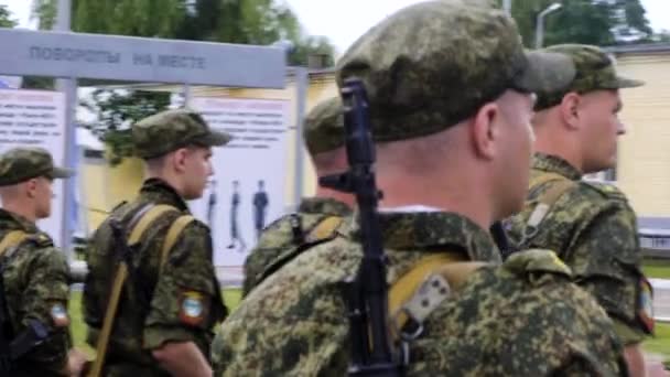 Vários cadetes militares de soldados com armas estão na praça em frente ao comandante ouvindo a ordem — Vídeo de Stock