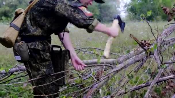 Military cadet soldier in camouflage uniform chopping a tree branch with an ax — Stock Video
