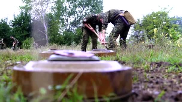 Plusieurs cadets militaires de soldats creusent un trou pour enterrer trois mines antichars à Tchernobyl pendant la pluie — Video