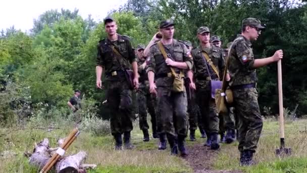 Varios soldados cadetes con uniforme militar marchan por un campo minado en un bosque de Chernóbil. Realizar una misión de combate. Un tipo bebe agua de un frasco. . — Vídeo de stock