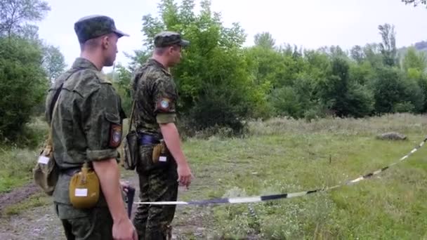 Oddíl chladných vojáků v armádních uniformách kontroluje vzdálenost roztažením pásky v Černobylském lese během deště — Stock video