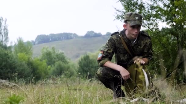 Військовий Курсант в Чорнобильську лісі сидить повороти стрічки, щоб перевірити відстань в дощ — стокове відео