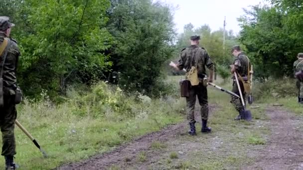 Tijdens de regen werken verschillende militaire cadetten van soldaten met schoppen in het Tsjernobyl-Bosveld. Twee antitankmijnen liggen op de grond — Stockvideo