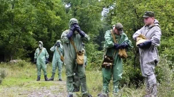 Verschillende militaire cadetten van soldaten zetten een beschermend pak op tegen straling in het Tsjernobyl-veld bos tijdens regen — Stockvideo