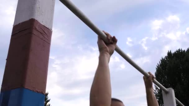 Homem atlético se puxa para cima em um bar horizontal em um acampamento militar para obter uma marca satisfatória . — Vídeo de Stock