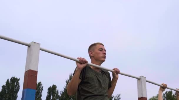 มอสโก - 28 กรกฎาคม นักกีฬาดึงตัวเองขึ้นบนแถบแนวนอนในค่ายทหารเพื่อให้ได้เครื่องหมายที่น่าพอใจ อุ่นเครื่องก่อนผ่านมาตรฐานที่ฐานทัพ — วีดีโอสต็อก