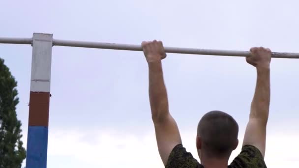 Moskva - 28 juli. Atletiska killar drar upp sig på en horisontell bar i ett militärt läger för att få ett tillfredsställande betyg. Värm upp innan du passerar standarder på en militärbas — Stockvideo