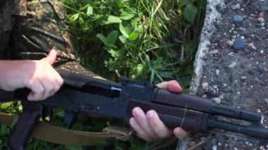 Çimlerdeki bir asker Kalaşnikof Ak-47 'nin kepenklerini açıyor.