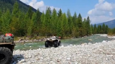 Novosibirsk, Rusya - 24 Mayıs 2019: Dörtlü nehri geçiyor. Genç adam bir dağ nehrinde su sıçramalarıyla seyahat ediyor. Off-road için Atv.