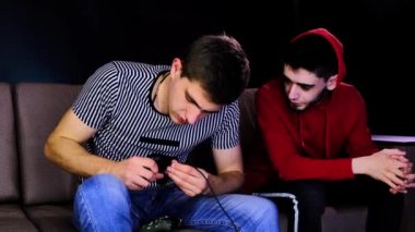 İki genç adam TV 'nin karşısında kanepede oturuyor ve bir oyun kumandasını kablolu yayına bağlıyorlar. Bir kablosuz kontrolörle oynarken insanlarla iletişim kurmak. Sade oda neon ışıklarıyla aydınlatılmış..