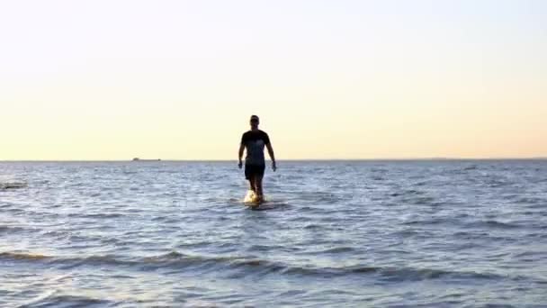 Silueta de hombre caminando por la playa al atardecer sobre el mar. Un tipo en activo paisaje marino de vacaciones de verano. Fantástico lugar natural de relax. El hombre camina hacia el mar, individual paseando sobre el agua . — Vídeos de Stock