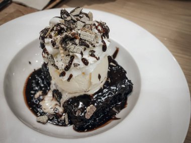 Üstünde krema ve dondurma olan çikolatalı kek.