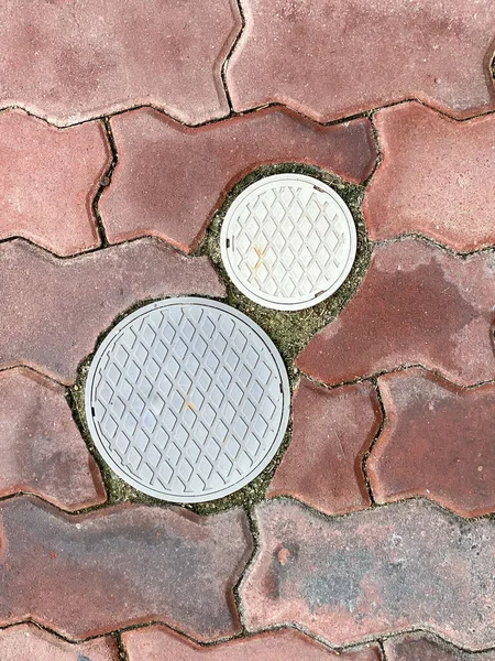 レンガの床の上に小さな円マンホールカバー — ストック写真