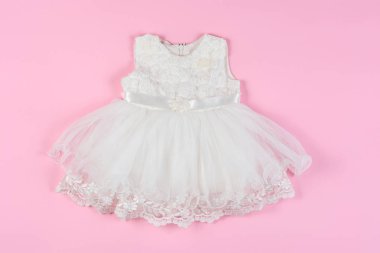 Çiçekli pembe bir arka plan üzerinde beyaz bebek elbise. Çocuk giyim, moda çocuk giyim kavramı.