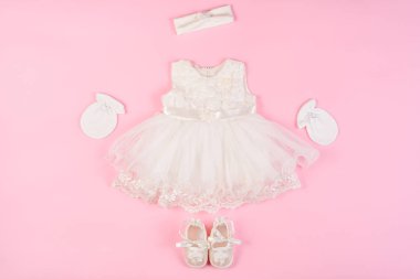 Güzel bebek elbise patik ve pembe bir arka plan üzerinde izole eldivenler