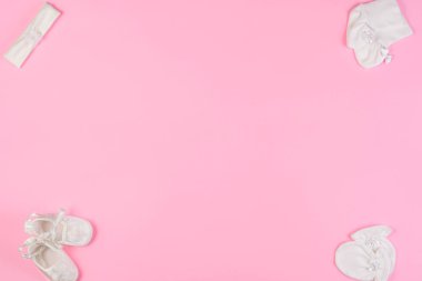 Pembe bir arka plan üzerinde üstten görünüm Bebek çorap, eldiven, saç bandı ve patik yeni doğan için. Metin için yer kopyalayın. Üstten görünüm.