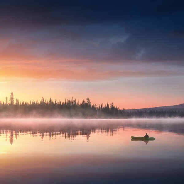 Man in kayak on river on scenic sunset