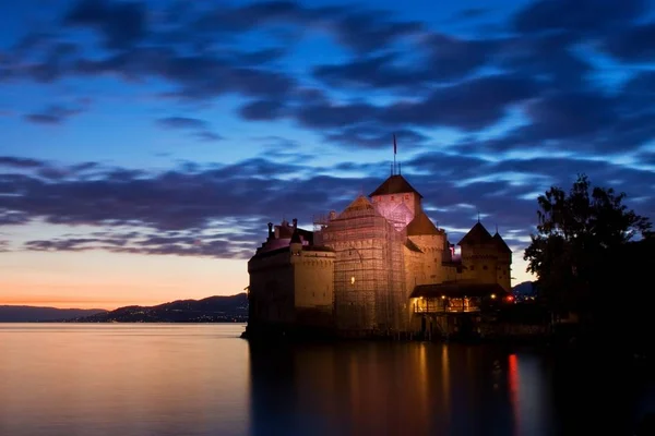 Scenic view of sea and castle in background under overcast sky