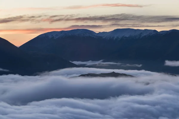 山谷被高山环境中的薄雾所淹没 在雾中 只有高山的最高峰在阳光灿烂的天空下升起 多雾的早晨美丽的风景概念 — 图库照片