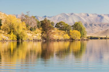 Ağaçlar ve dağlar ile kuru manzara Göl. Sudaki yansımaları ile yatay görüntü. Güzel arka plan fotoğrafçılığı konsepti.
