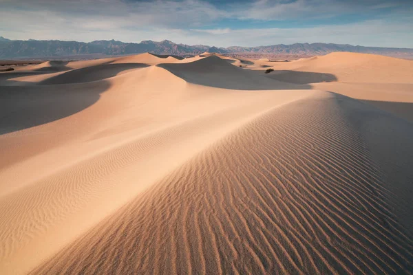 Early Morning Sunlight Over Sand Dunes And Mountains At Mesquite flat dunes, Death Valley National Park, California USA Stovepipe Wells sand dunes, very nice structures in sand Beautiful background