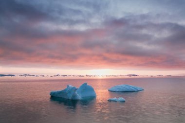 Grönland icefjord buzdağları ile Arktik doğa manzara gece yarısı güneş günbatımı / ufukta gündoğumu ile. Gece yarısı sezonunda erken sabah yaz alpenglow. Ilulissat, Batı Grönland.
