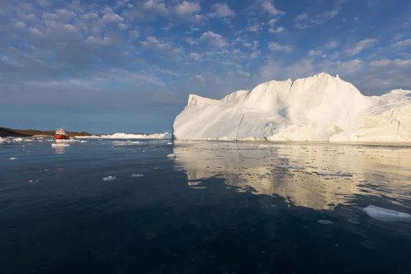 氷山の中の小さなボート真夜中の太陽イルリサット グリーンランドの間にディスコ湾の氷河の浮遊氷山の間でヨットクルージング 地球温暖化氷と氷山現象の研究 — ストック写真