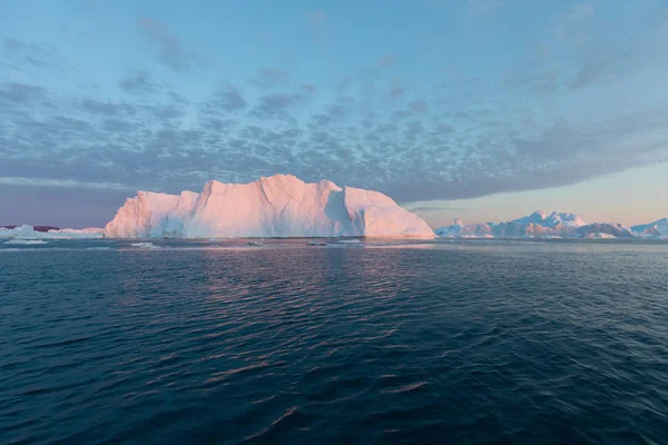 西グリーンランドのディスコ湾には さまざまな形の巨大な氷山があります 彼らの情報源はヤコブスハーン氷河である これは地球温暖化と氷の壊滅的な融解の現象の結果です — ストック写真