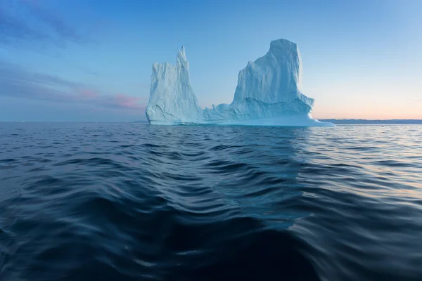 日没時の興味深く青い空の下でフォトジェニックで複雑な氷山 自然界における地球温暖化の影響南極やグリーンランドの深い青い水の氷河の融解の概念像 — ストック写真